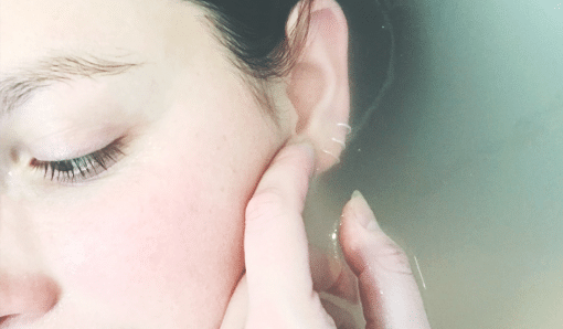 Woman stroking her own face in the bath