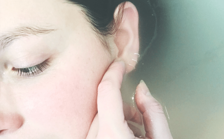 Woman stroking her own face in the bath