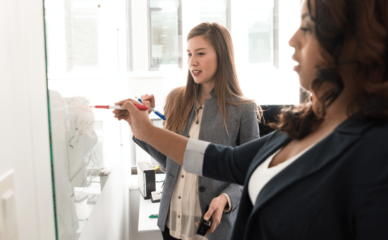 Two women working at a whiteboard